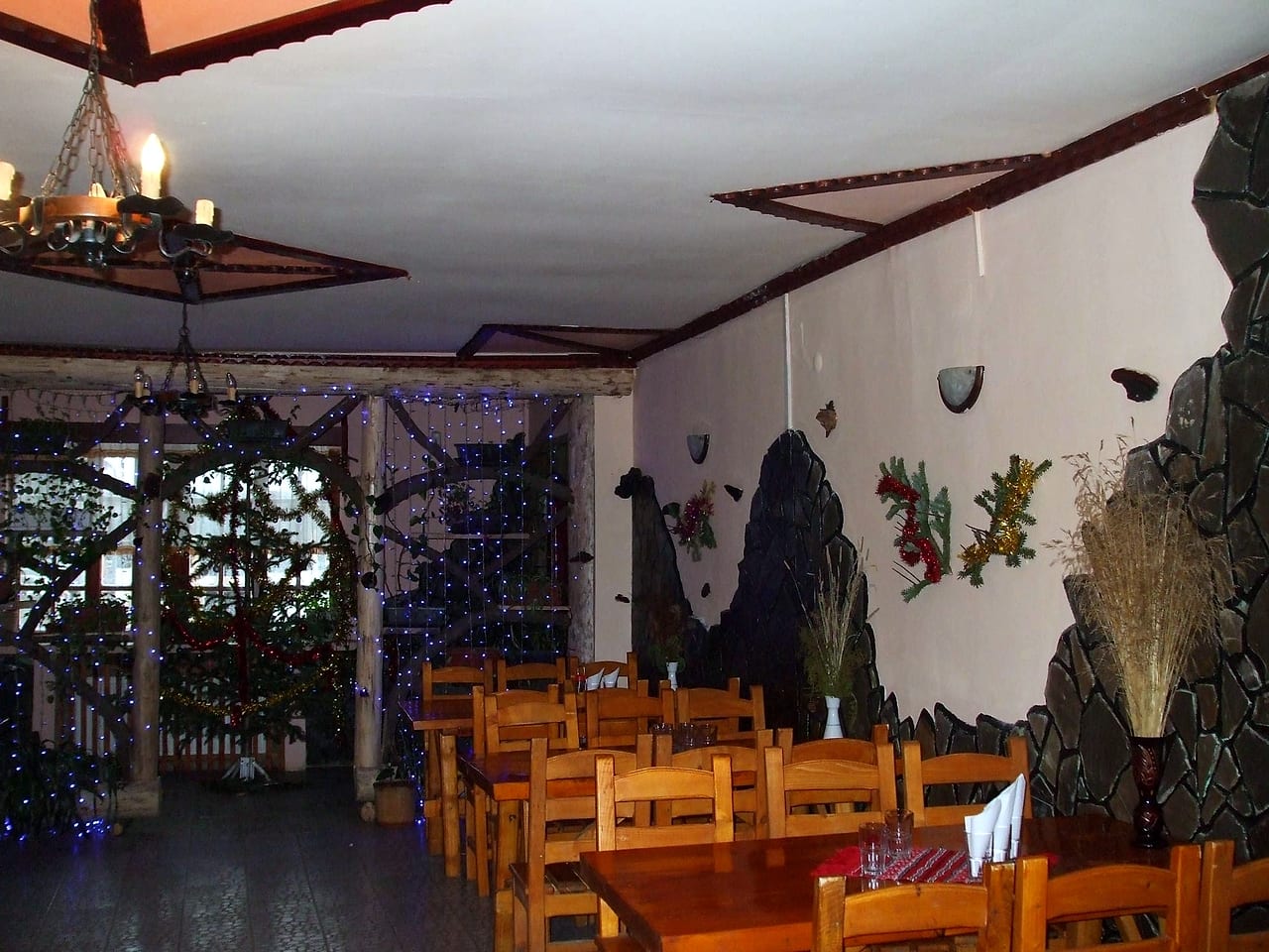 Sala mare a restaurantului, cu mese de lemn deschis, candelabru de fier și decorații de sărbători.